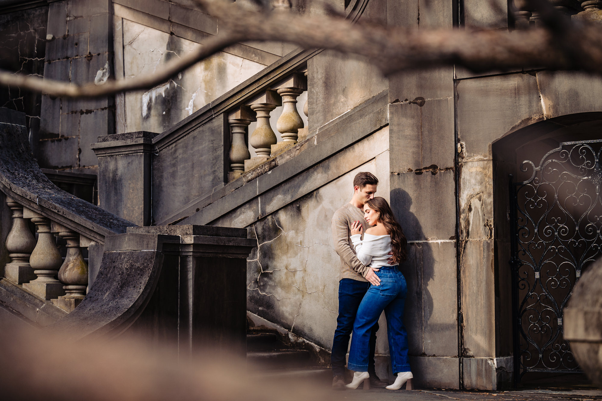 The couple shares an intimate moment, wrapped in a loving hug against the backdrop of a striking concrete structure.