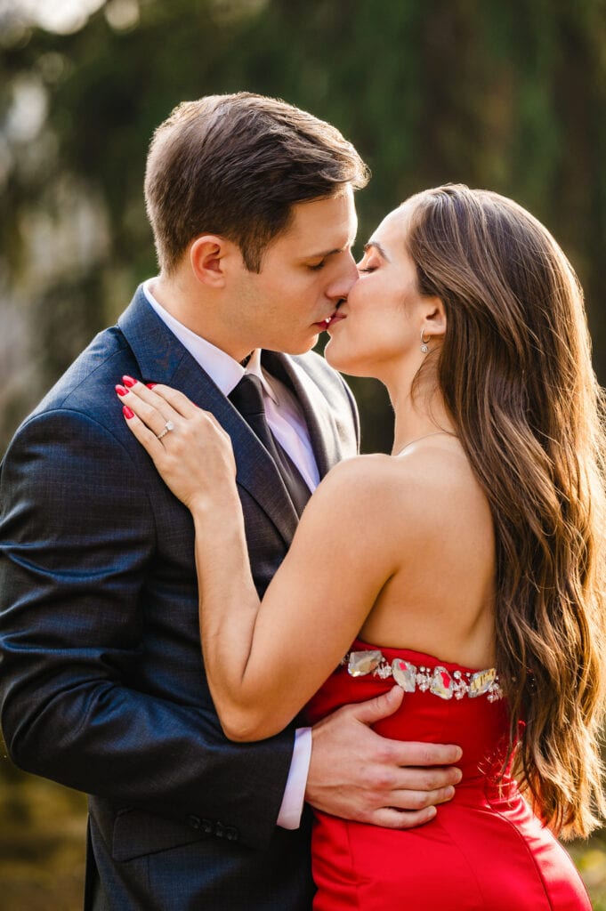 Couple shares a heartfelt kiss surrounded by the vibrant fall hues of Winterthur garden, a stunning portrait capturing the essence of the season's beauty.