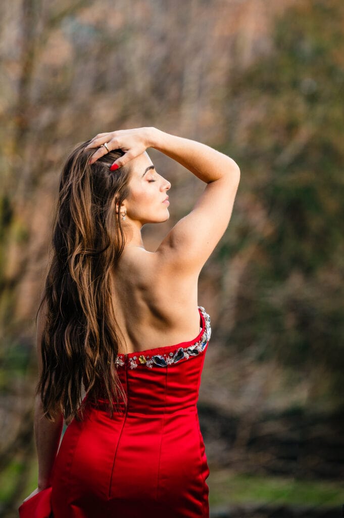 Woman gracefully touches her head in the enchanting Winterthur garden, captured during the vibrant autumn for a stunning portrait session