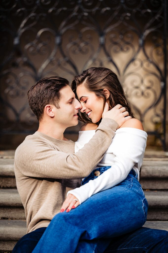 Captured in an intimate moment, the engaged couple shares a tender embrace against the backdrop of a striking concrete structure, savoring their love.
