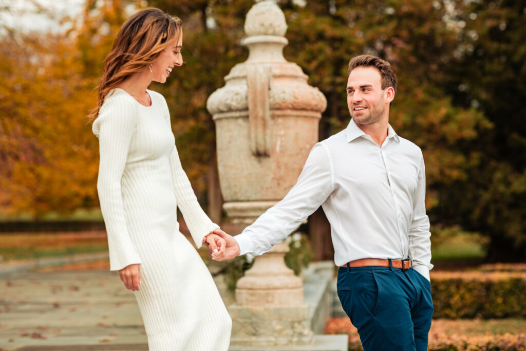 Endearing moment captured during the Nemours Estate engagement photoshoot, as the man looks at the woman with a smile. Hand in hand, they gracefully descend the stairs, sharing genuine smiles that reflect the joy of their love and the enchanting surroundings.