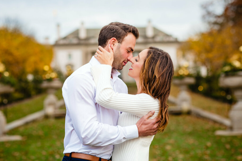Intimate moment frozen in time, as a woman delicately holds the man's cheek, and he reciprocates by holding her back. Both lean in towards each other, capturing the anticipation and tenderness of a shared kiss between the couple.