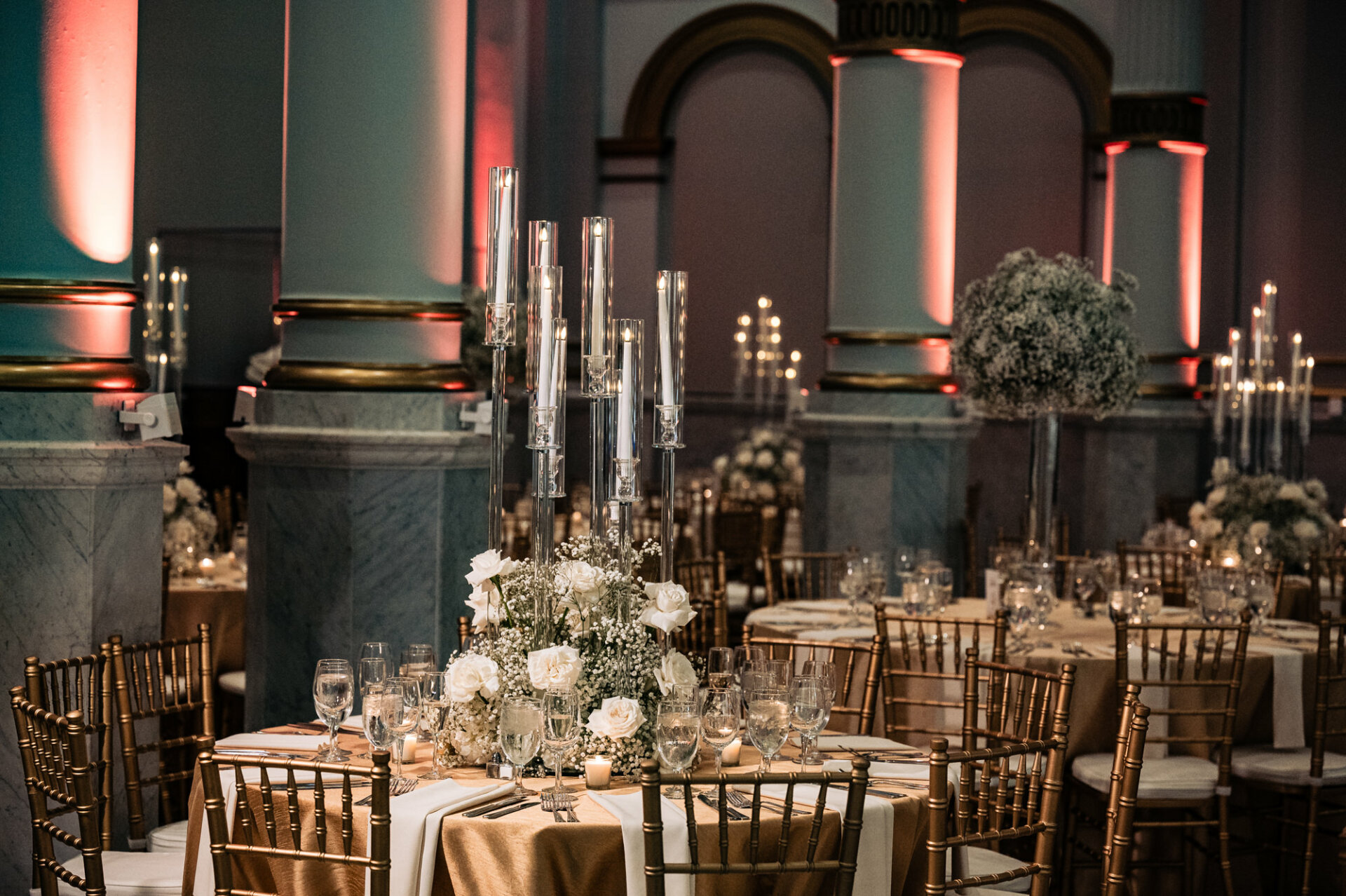 shot of gold accented chairs and tables draped in gold cloth, with roses adorned the center of each tables