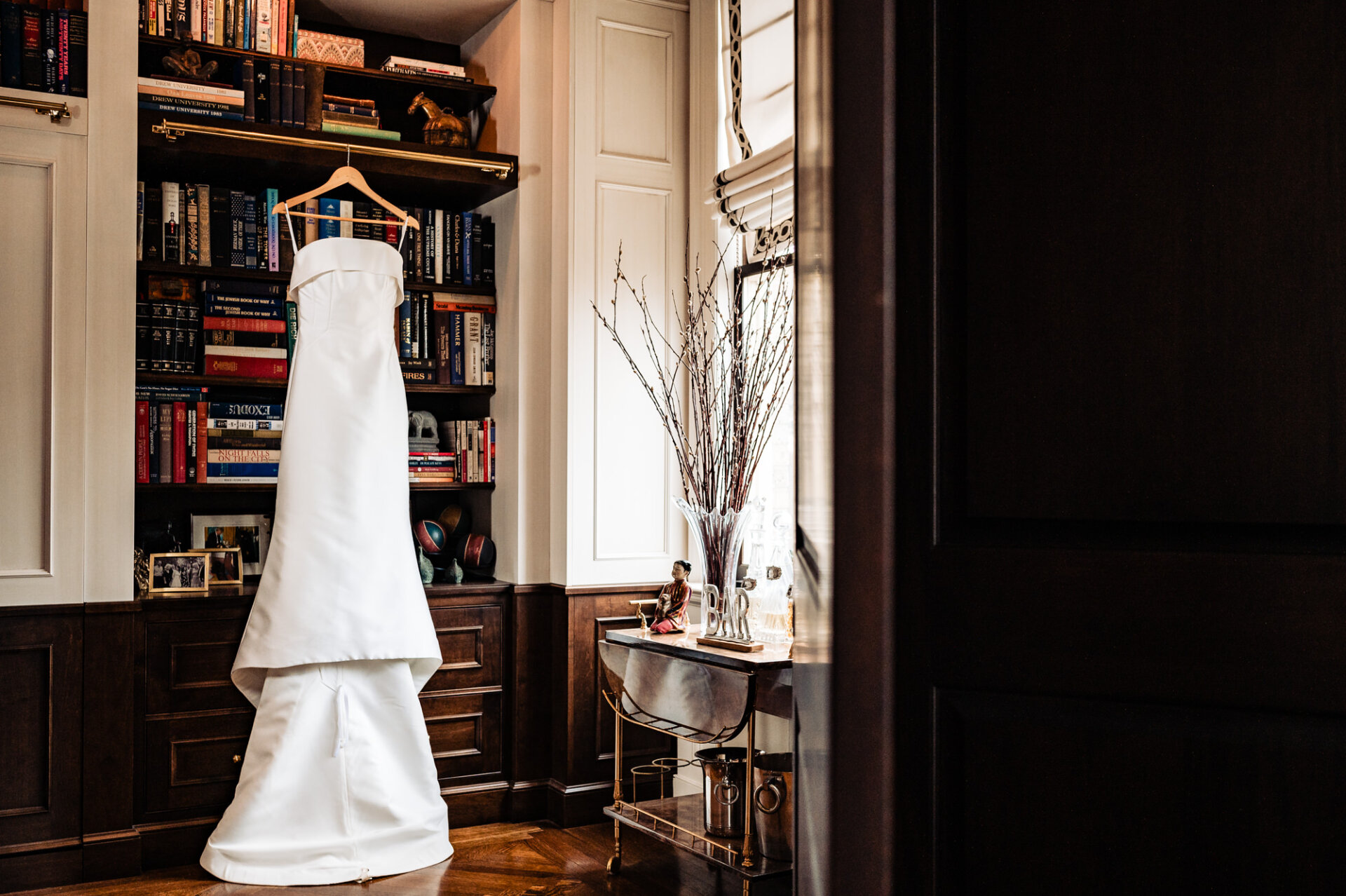 A shot showcasing the bride's stunning silk white wedding dress, a Trumpet gown crafted from mikado scuba fabric, featuring an elegant arched strapless neckline adorned with a classic cuff detail.