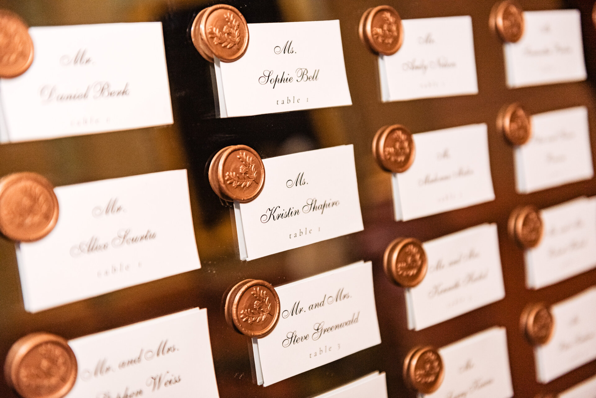 A beautifully designed table card awaits each wedding guest, elegantly displaying their designated seating arrangement and adding a touch of sophistication to the reception décor.