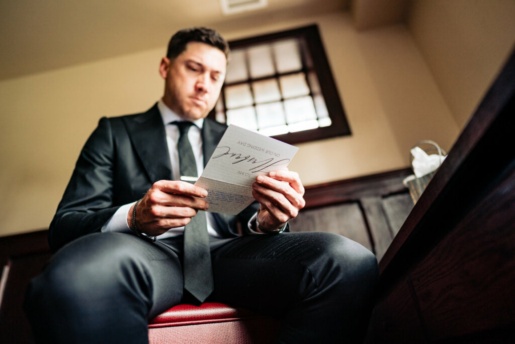 Groom reads a heartfelt letter from his bride, moments before their wedding ceremony, capturing a tender moment of anticipation and love.