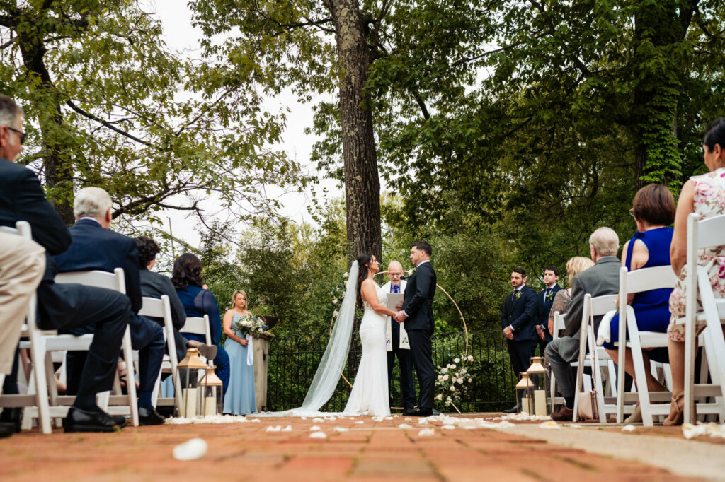 The bride and groom stand hand in hand, surrounded by the beauty of nature, as they exchange heartfelt vows