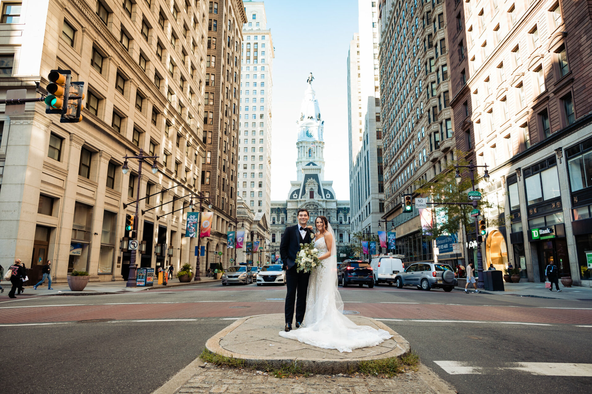 In a picturesque moment against the iconic backdrop of Philadelphia City Hall, the bride and groom stand at the heart of the street, surrounded by the hustle and bustle of the city.