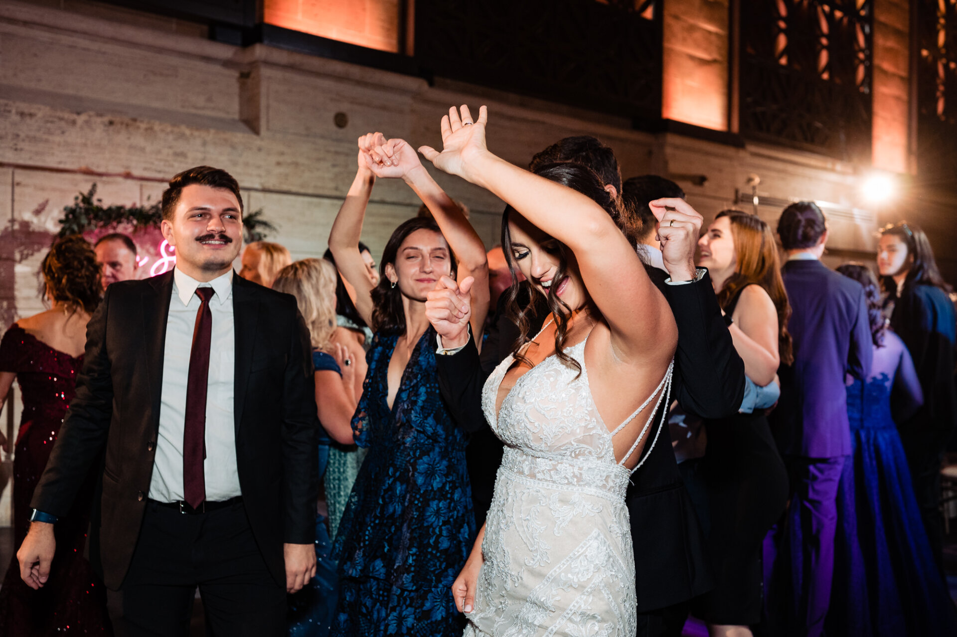 The newlyweds hit the dance floor with their guests, their smiles radiating happiness as they create unforgettable memories together on this joyous night.