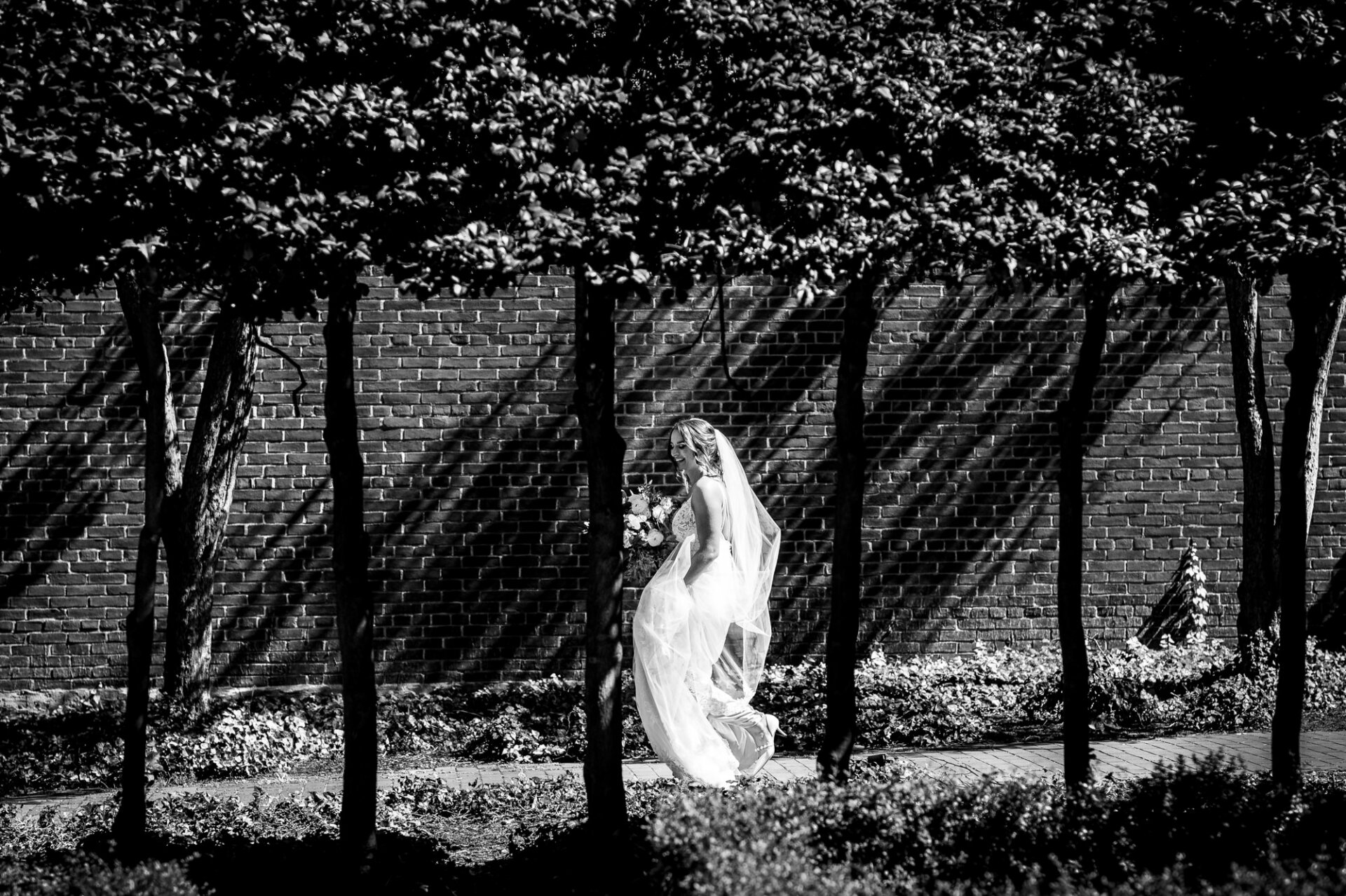 In this striking black and white image, the bride is captured with excitement as she walks down the alleyway towards her groom.