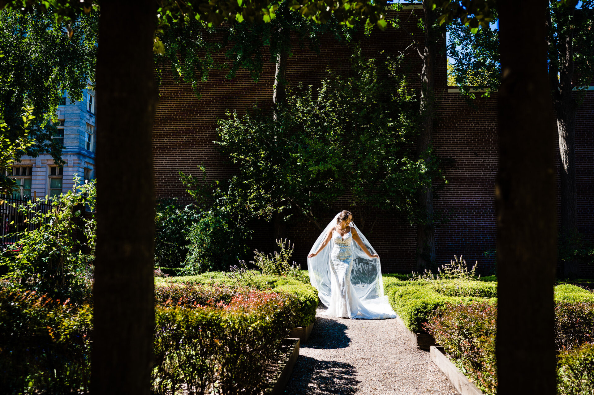 the bride stands gracefully amidst a lush garden, her veil softly flowing in the gentle breeze