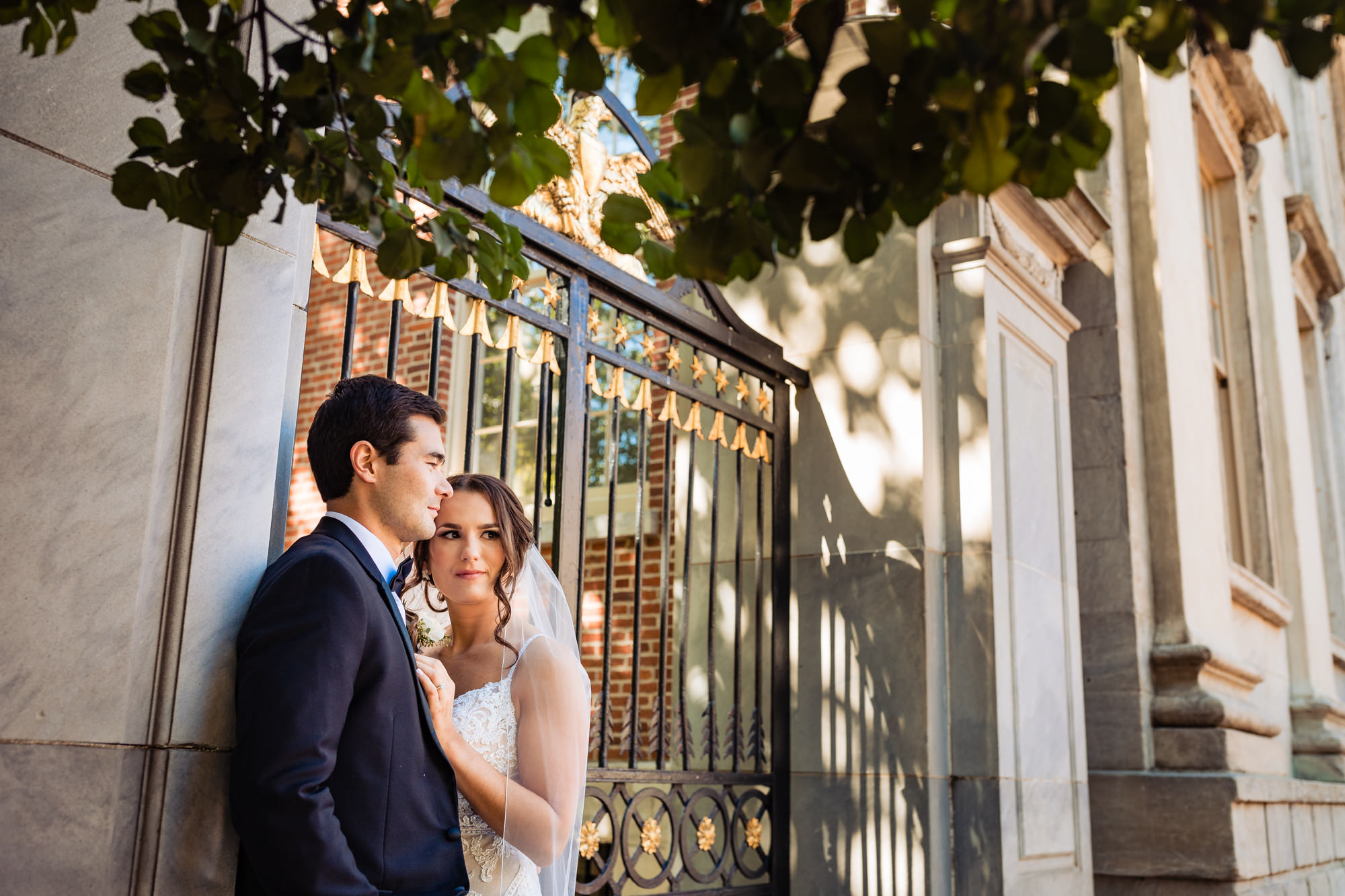 the bride and groom strike a pose for the camera with a steel gate as their backdrop.