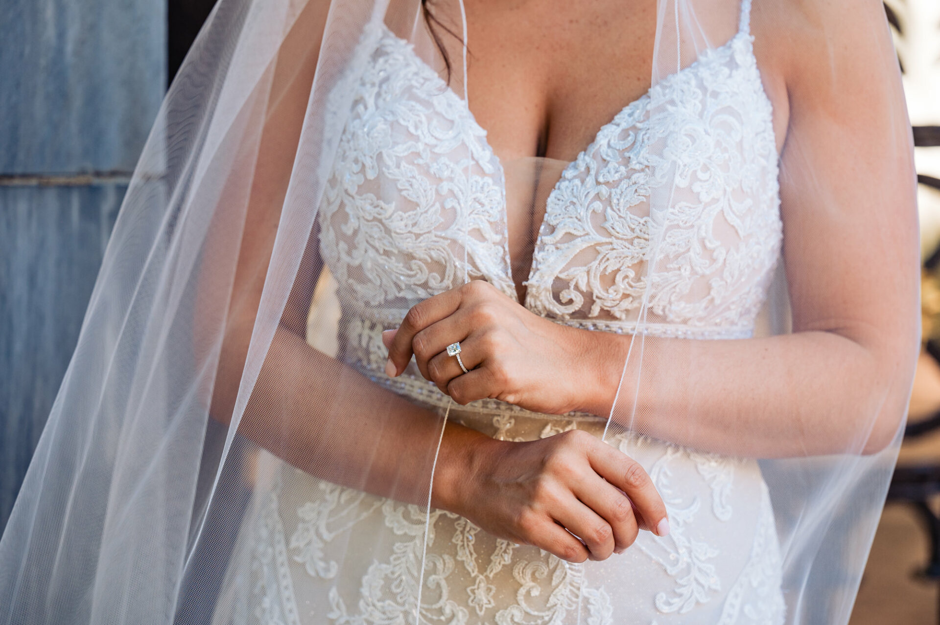 the intricate details of the bride's gown are showcased alongside her dazzling engagement ring in a breathtaking close-up shot