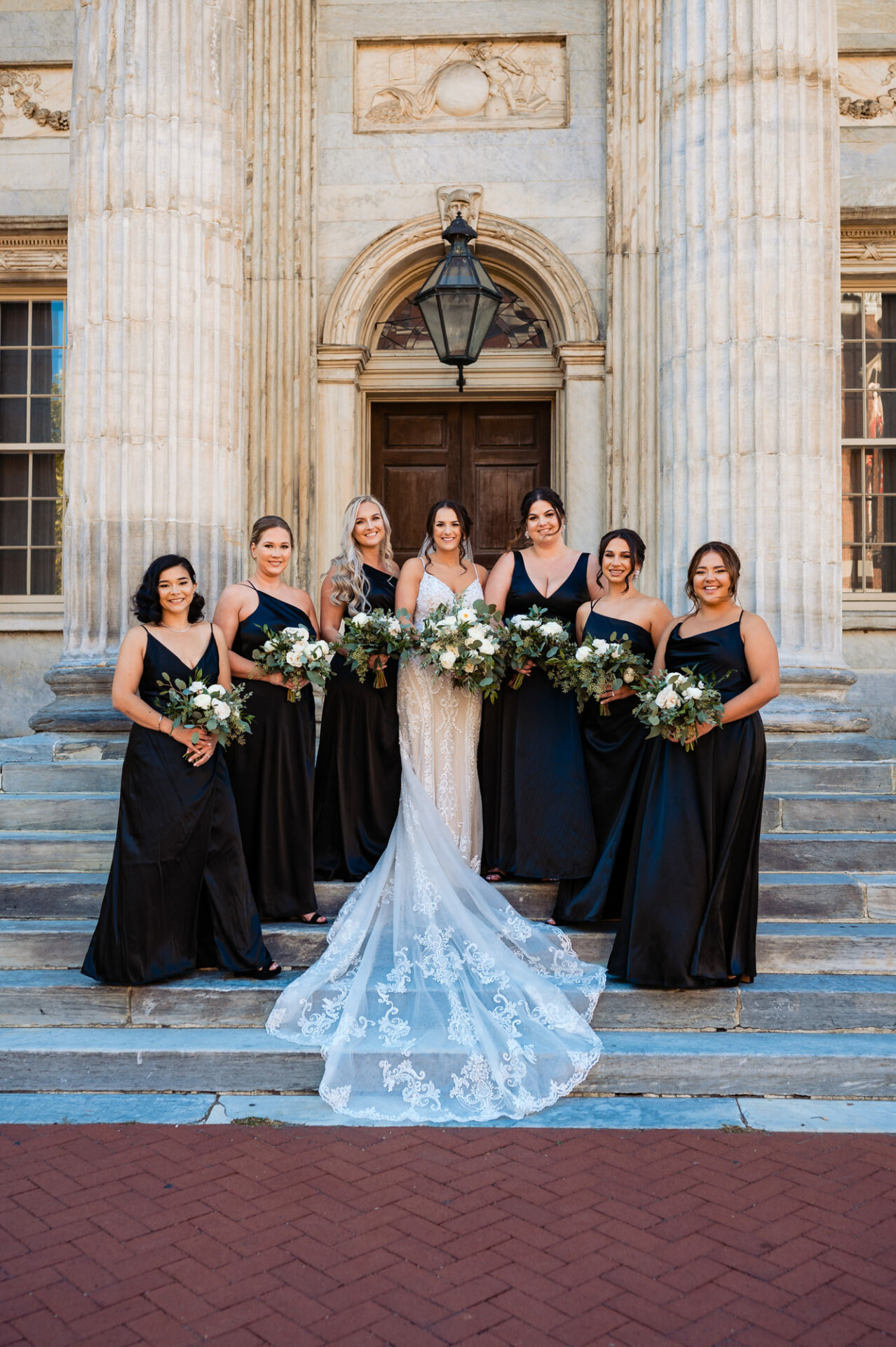 The bride shares a joyous pose with her bridesmaids, surrounded by smiles and camaraderie.