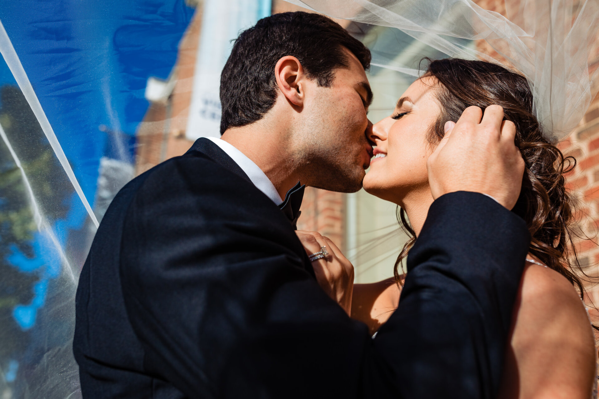 the groom gently lifts his bride's veil and plants a tender kiss upon her lips