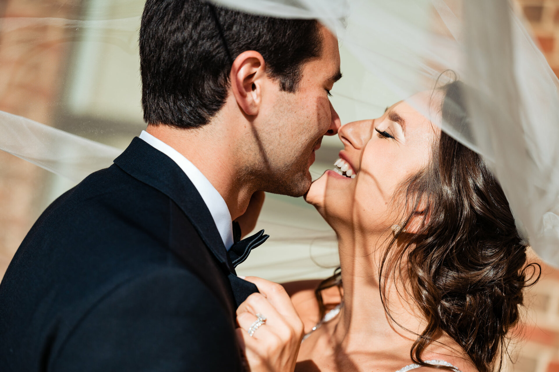In a moment filled with tenderness and love, the groom gently lifts the bride's veil and plants a tender kiss on her lips.