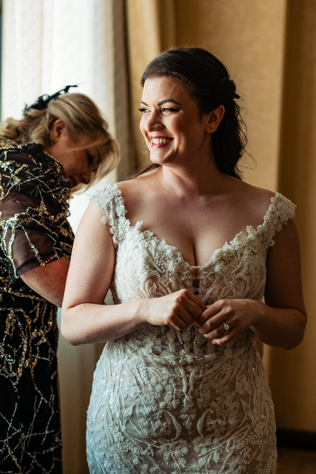 Tender mother-daughter bond: Bride smiles serenely as her mother attends to her gown, creating a touching bridal moment