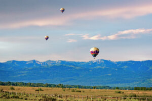 Ballooning enthusiasts take to the skies above Jackson Hole, Wyoming, floating serenely amidst the breathtaking vistas of the Teton Mountains and vast wilderness below, in a mesmerizing display of aerial exploration and natural beauty.