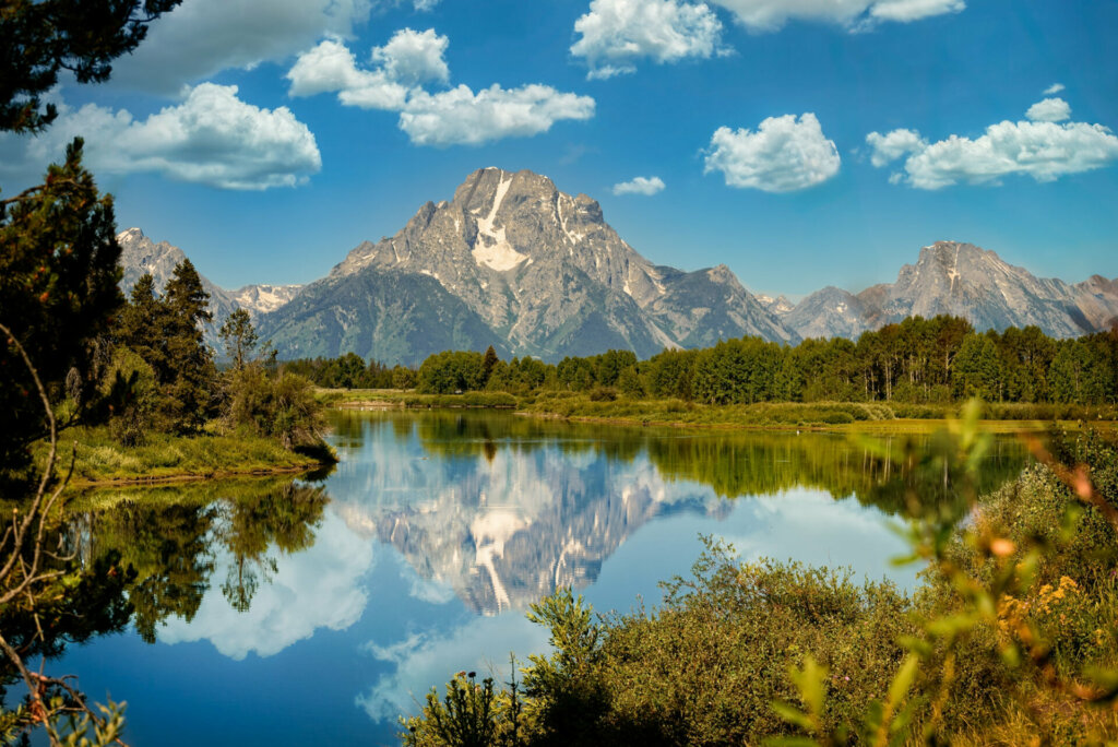 A serene and reflective lake nestled amidst the breathtaking landscapes of Yellowstone National Park, mirroring the towering peaks and vibrant colors of the surrounding wilderness