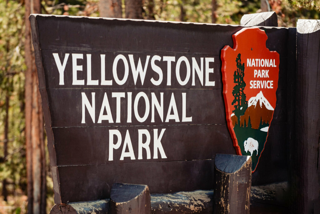 The signboard of Yellowstone National Park, featuring the iconic yellow stone with the park's name, welcoming visitors to explore its natural wonders and diverse landscapes.