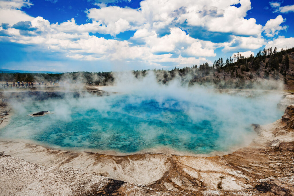 The Old Faithful geyser basin at Yellowstone National Park, showcasing a landscape of colorful geothermal features, steam rising from various geysers and hot springs, surrounded by the natural beauty of the park's wilderness