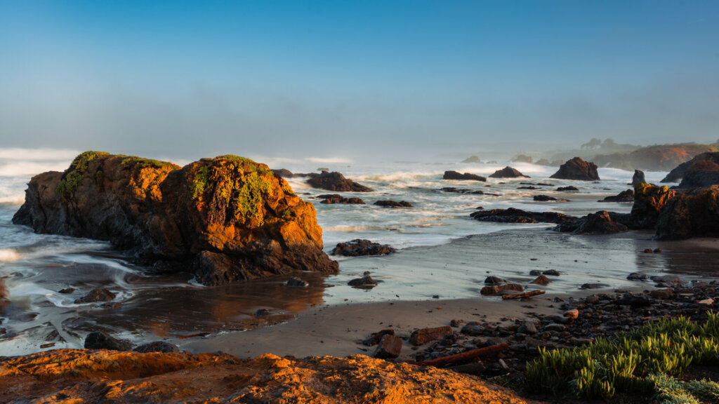 The rocky shoreline at Fort Bragg, California, presents a rugged and stunning coastal landscape. Jagged rock formations jut out from the shoreline, sculpted by the relentless action of the Pacific Ocean over millennia.