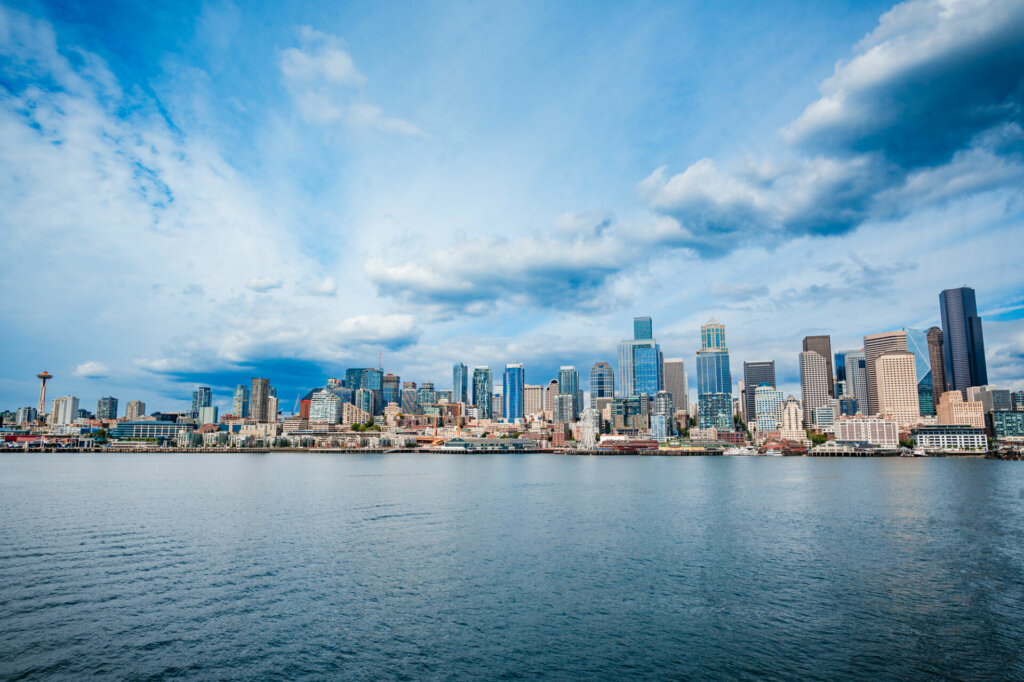 A panoramic view of downtown Seattle captured from the water, showcasing the city's iconic skyline, with towering skyscrapers, bustling waterfront, and the majestic Puget Sound in the foreground.