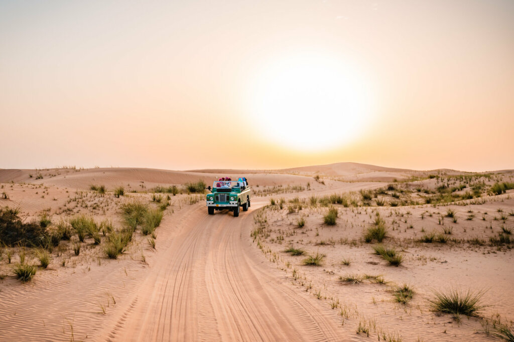 A group of people rides a jeep across the vast desert landscape