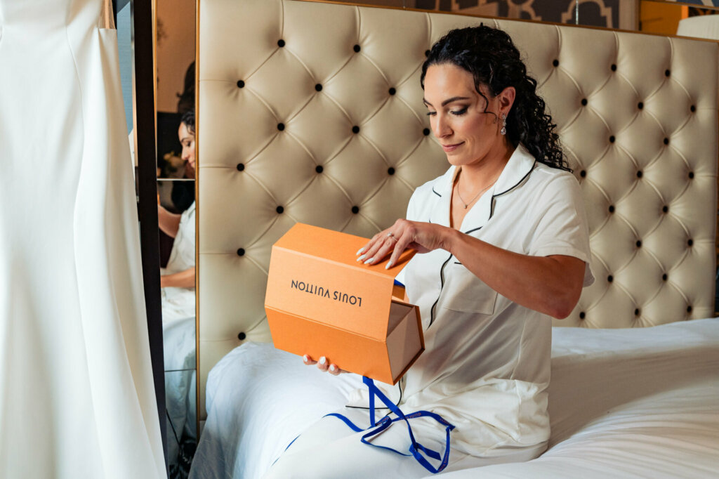 The bride, dressed in her robe, opens an LV box gifted by her groom, revealing a special present.