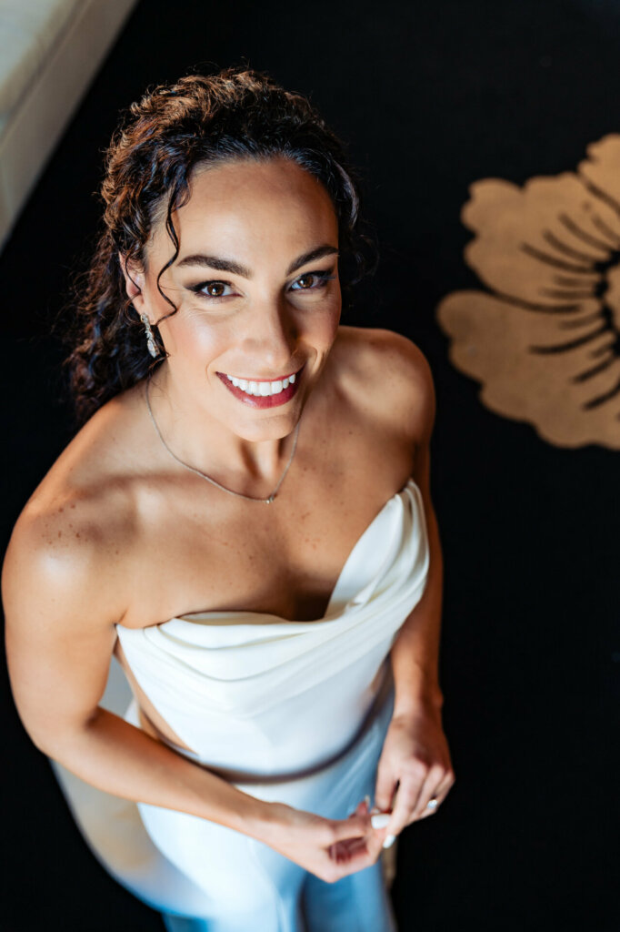 The bride beams with joy as she smiles for the camera, radiating happiness on her special day.