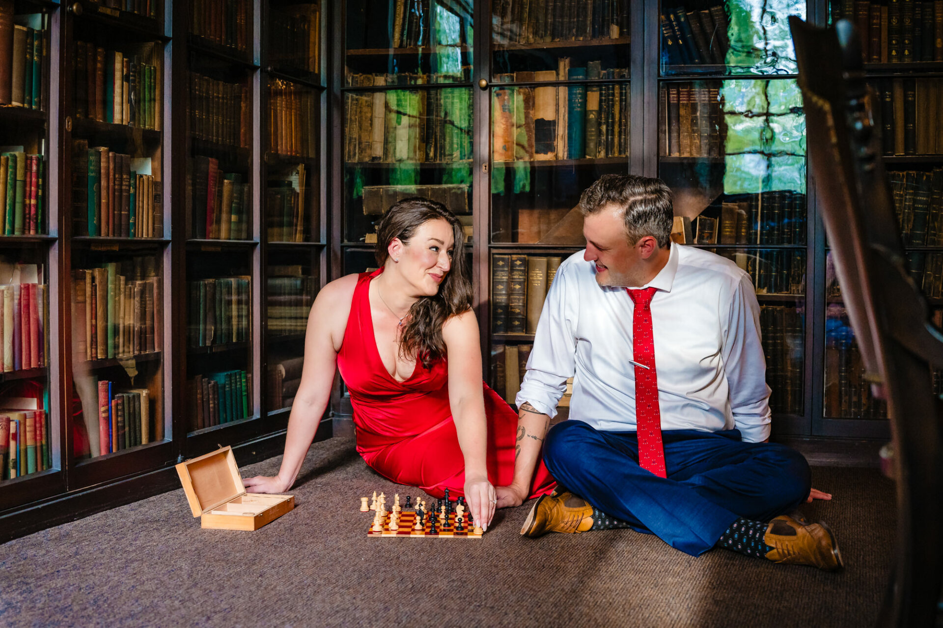 A couple, absorbed in a chess match, sits on the plush carpet of Carpenter's Hall's historic library