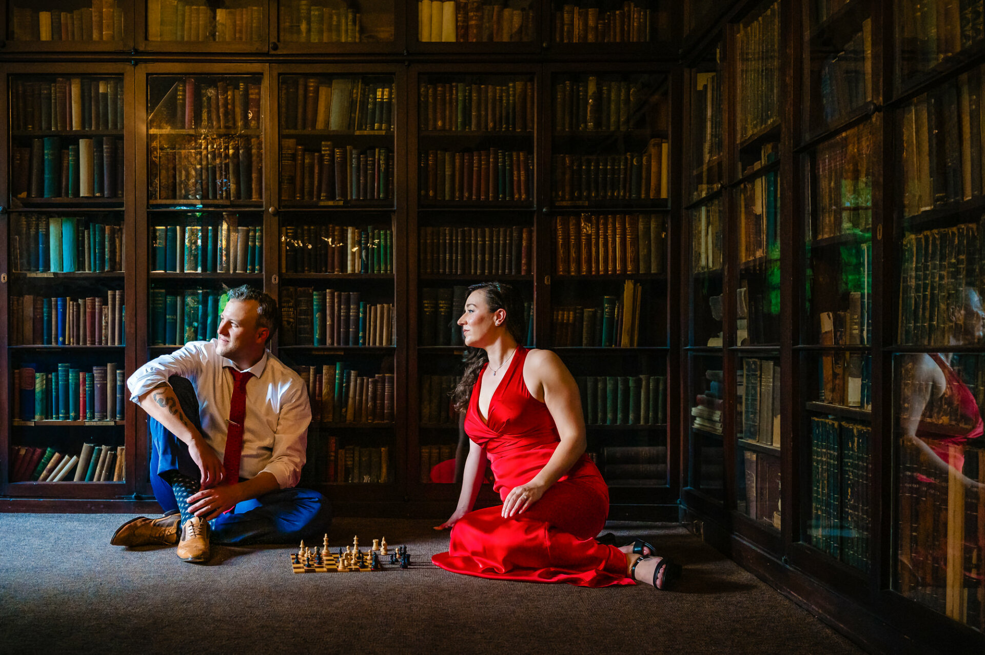 A couple shares a tender moment on the carpeted floor of Carpenter's Hall's historic library during their engagement shoot.