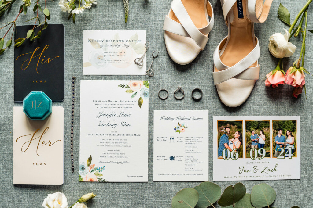 A collection of wedding elements including handwritten vows and letters, bride's accessories and heels, and an elegantly displayed invitation on a gray background with floral accents.