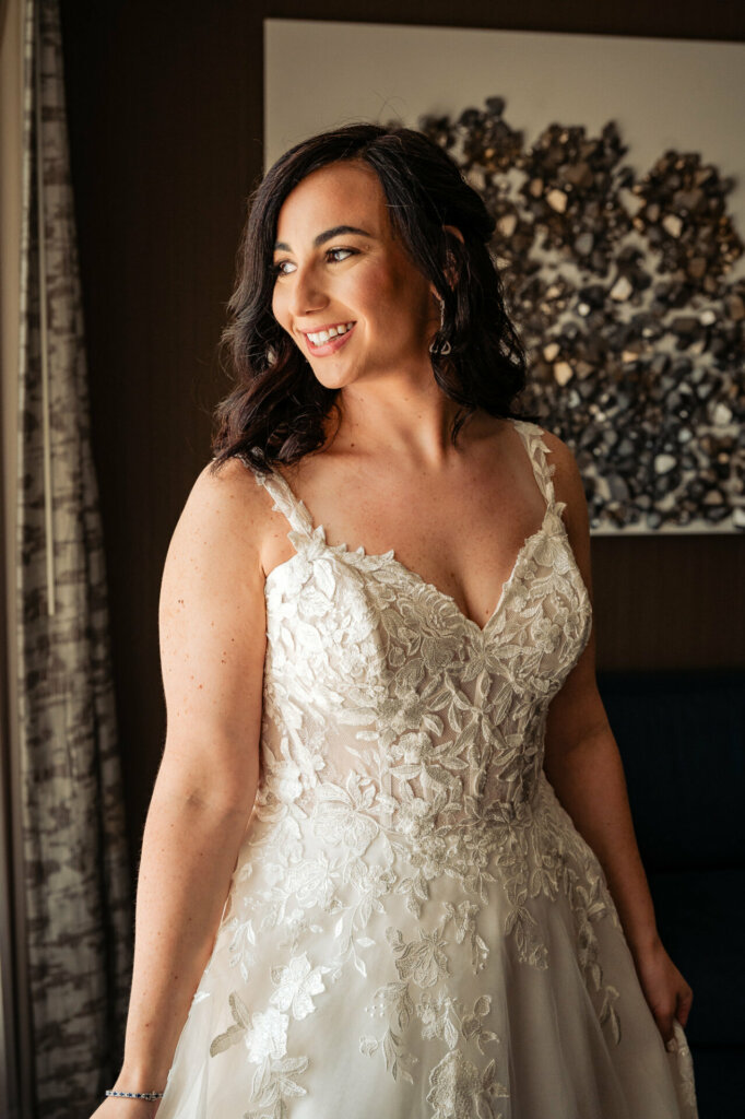 Radiant bride in her wedding gown, smiling warmly while looking to the side.