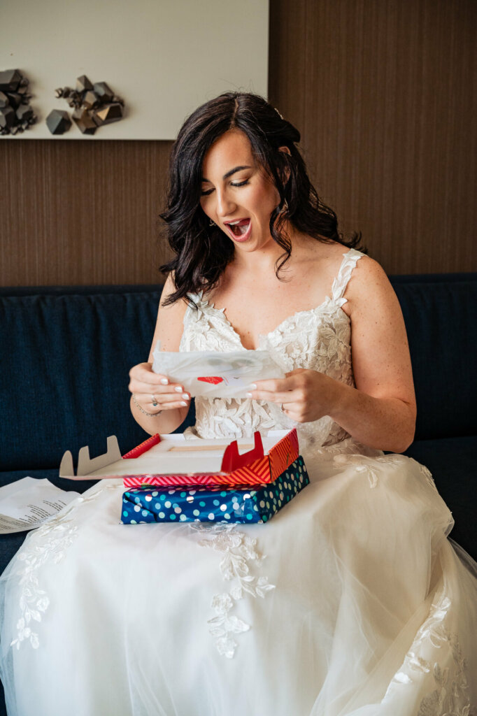 Bride's face expressing delighted surprise as she reacts to the opened wedding gifts.