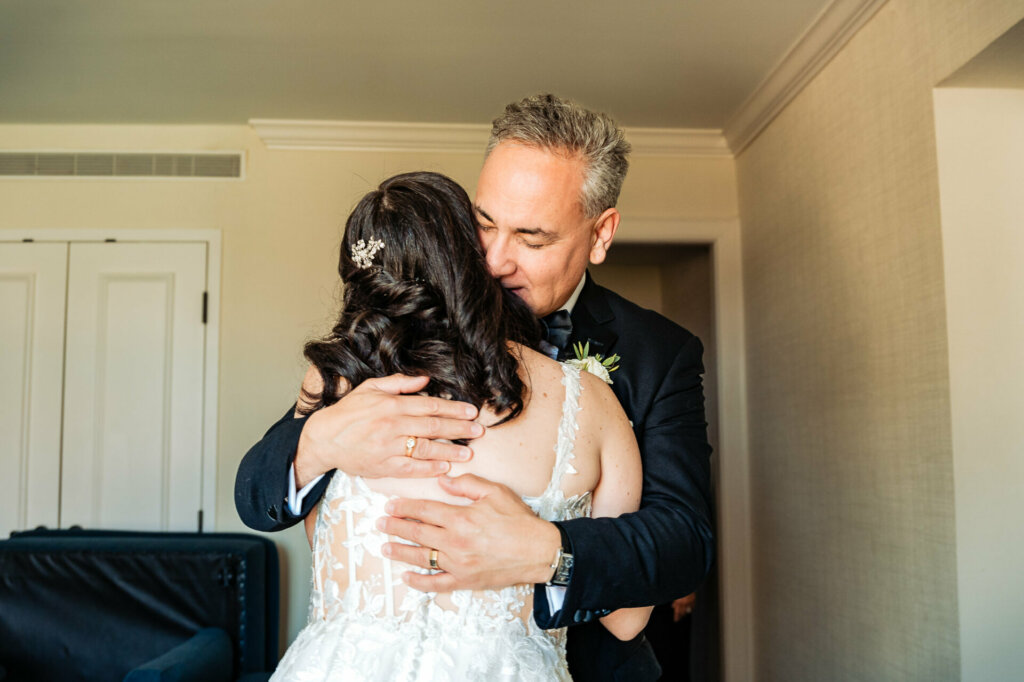 Emotional moment as the father embraces his daughter upon seeing her in her wedding gown for the first time.