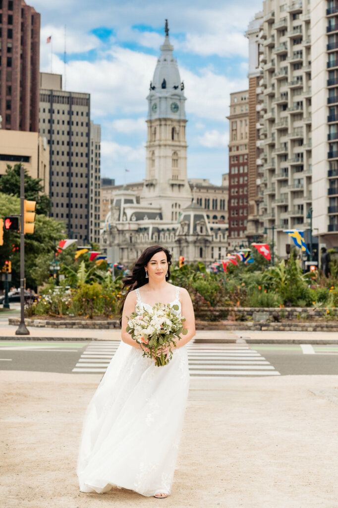 Elegant bride holding a bouquet, standing in the midst of a cityscape with towering buildings in the background.