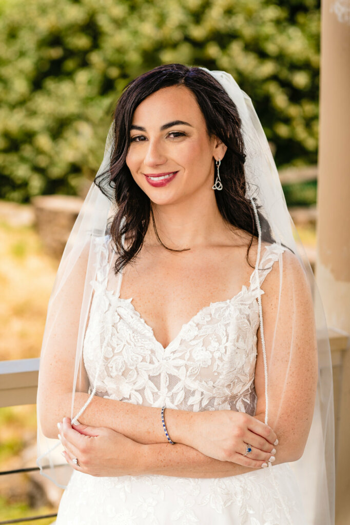 Close-up bridal portrait: radiant bride with natural makeup, wearing white wedding gown and veil, smiling warmly at camera