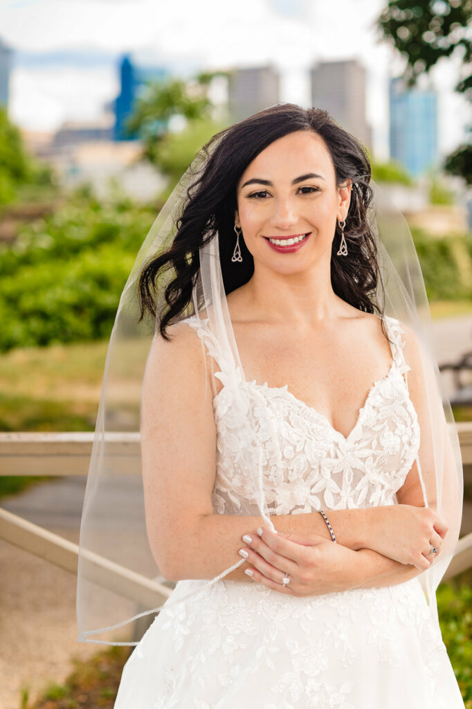 Close-up bridal portrait: radiant bride with natural makeup, wearing white wedding gown and veil, smiling warmly at camera