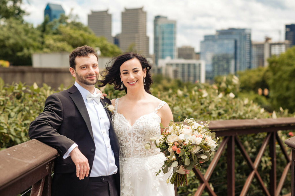 Happy newlyweds posing together, the bride holding her bouquet as they both smile radiantly.