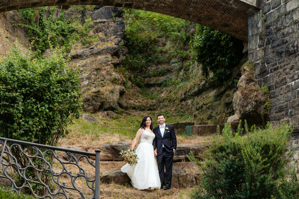 bride and groom pose for their portrait while being silhouetted against a breathtaking landscape of towering rocks.