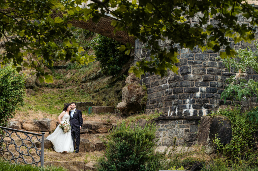 bride and groom pose for their portrait while being silhouetted against a breathtaking landscape of towering rocks.
