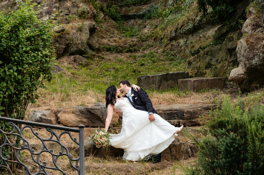 Bride dips for a tender kiss with her groom, dwarfed by the majesty of towering rocks.
