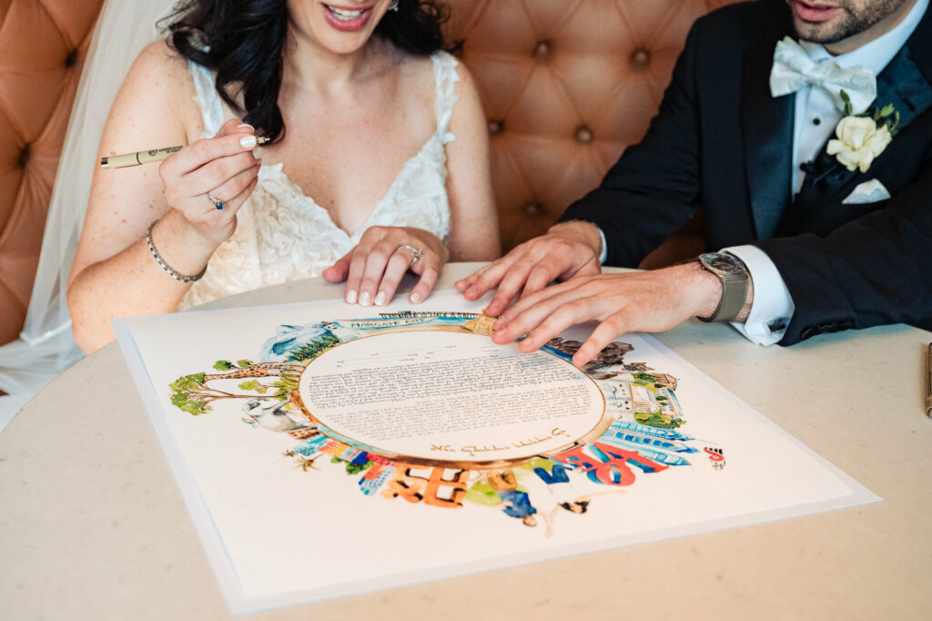 Bride and groom attentively review and sign the ketubah