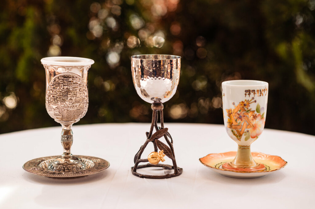Two silver Kiddush cups, traditionally used for blessings during the Jewish wedding ceremony, rest on a decorative cloth.