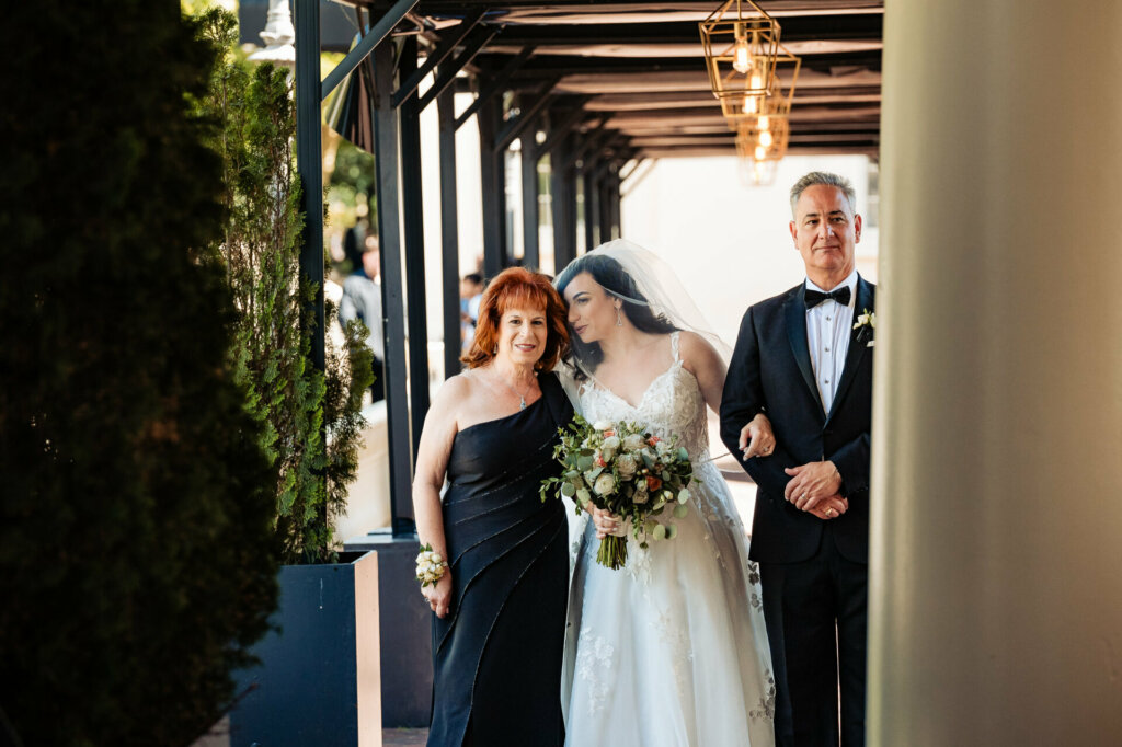 A radiant bride, surrounded by her loving parents, shares a heartfelt moment as they prepare for the walk down the aisle.