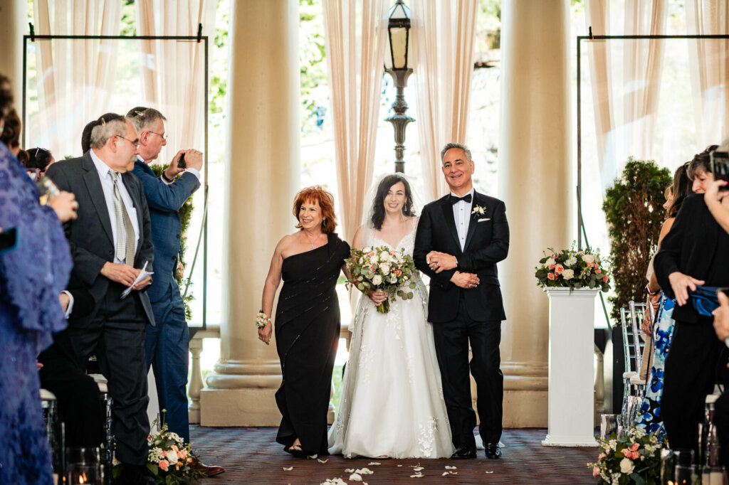 Proud parents escort their radiant daughter down the aisle, embarking on a new chapter as husband and wife.