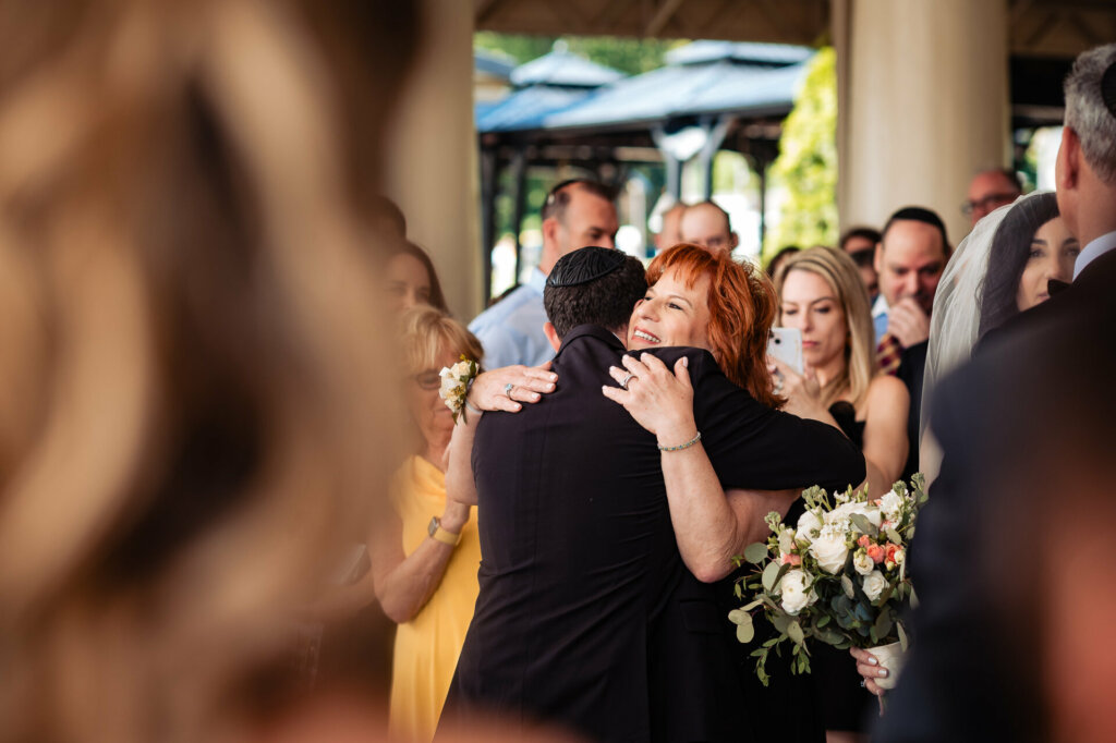 Groom receives a warm hug from his mom, filled with love and support, before walking down the aisle to meet his bride.