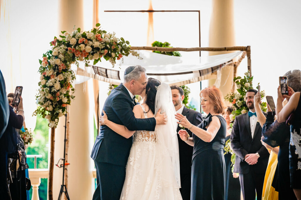 Emotional moment as a proud father embraces his tearful bride after walking her down the aisle.