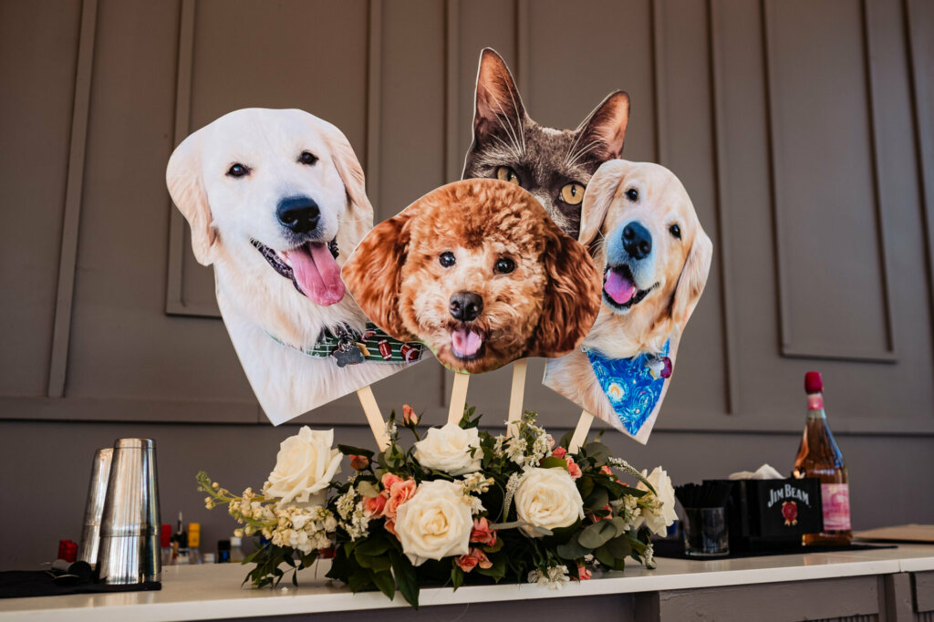 Cut-out pictures of the newlyweds' pets displayed atop floral arrangements as wedding decor.
